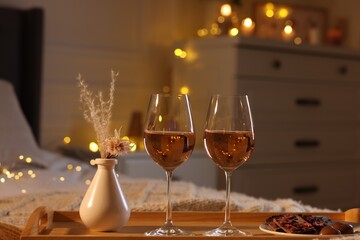 Tray with glasses of wine on bed. Romantic evening