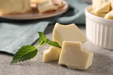Pieces of tasty white chocolate and mint on grey table, closeup