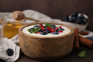 Bowl of delicious semolina pudding with blueberries, pomegranate and mint on table, closeup