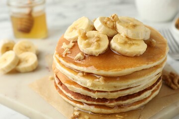 Delicious pancakes with bananas, walnuts and honey on table, closeup