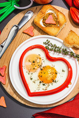 Heart-shaped fried egg served with toasted bread. Romantic art food idea for Valentine's breakfast