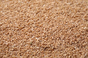 Dry organic wheat groats as background, closeup