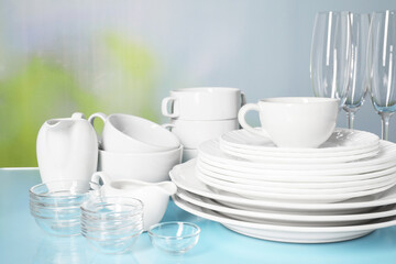 Set of clean dishes and glasses on light blue table