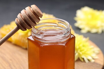 Sweet honey in jar and dipper on table, closeup