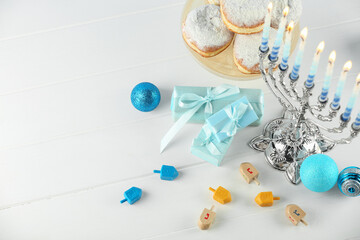 Composition with Hanukkah menorah, dreidels and gift boxes on white wooden table, above view. Space for text