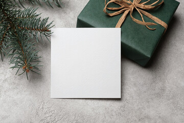 White square paper card mockup with gift box on grey concrete background, blank card mock up with...