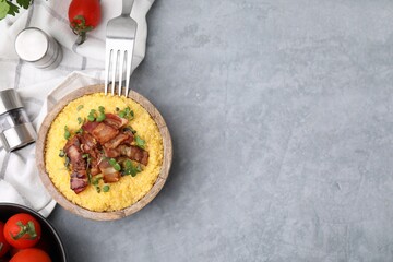 Cooked cornmeal with bacon and microgreens in bowl on light grey table, top view. Space for text
