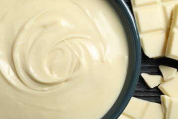 Tasty white chocolate paste in bowl and pieces on table, top view