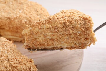 Taking piece of delicious Napoleon cake from table, closeup
