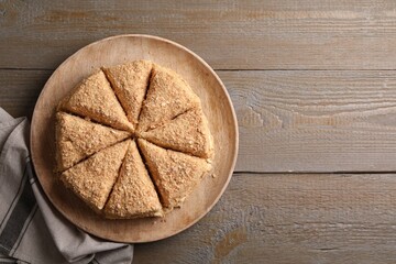Delicious cut Napoleon cake on wooden table, top view. Space for text
