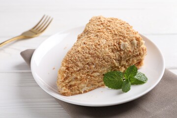 Piece of delicious Napoleon cake served on white wooden table, closeup