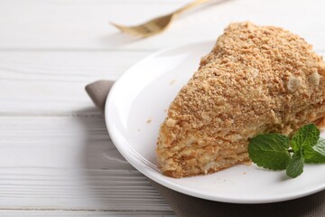 Piece of delicious Napoleon cake on white wooden table, closeup