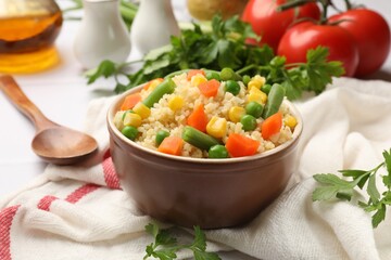 Delicious bulgur with vegetables in bowl served on table, closeup