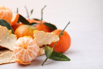 Many fresh ripe tangerines and leaves on white table, space for text, closeup