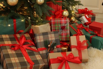 Many gift boxes under beautiful Christmas tree in room