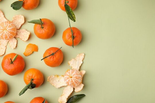 Many fresh ripe tangerines and leaves on light green table, flat lay. Space for text