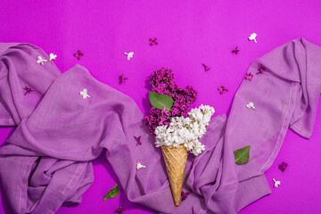 White and violet lilac flowers in waffle ice cream cones on purple background. Flat lay