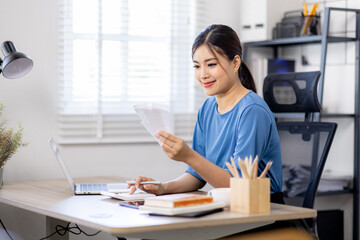 asian woman using calculator and calculate bills in home office. tax form us business income office...