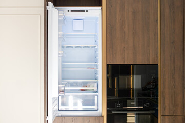 Fototapeta premium Kitchen furniture with an open refrigerator built-in microwave and oven