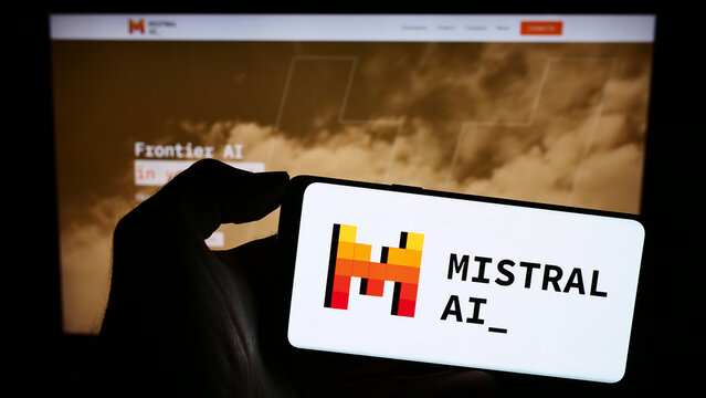 Stuttgart, Germany - 11-27-2023: Person holding mobile phone with logo of French artificial intelligence company Mistral AI SAS in front of web page. Focus on phone display.