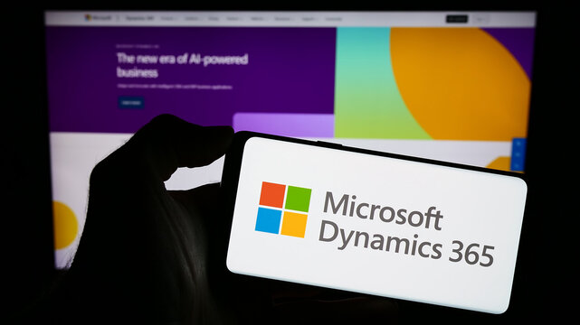 Stuttgart, Germany - 11-27-2023: Person holding cellphone with logo of accounting software product Microsoft Dynamics 365 in front of company webpage. Focus on phone display.