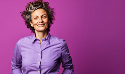 Confident Central European non-binary person in their 40s with curly hair, wearing a lilac shirt, standing against a purple background