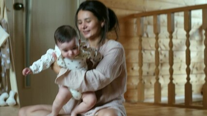 A joyful mother lifts her baby, their connection palpable in a cozy home setting. It's a celebration of maternal bliss.