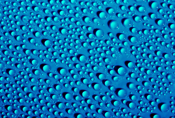 Water drops on glass as a background. Condensation on a cold drink. Blue background with drops texture.