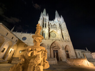 View of the medieval metropolitan cathedral of Burgos (Spain), with its French Gothic style facade and towers, illuminated at night.