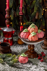 Homemade pink marshmallows in the shape of pumpkins surrounded by Christmas decorations.