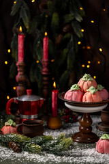 Homemade pink marshmallows in the shape of pumpkins surrounded by Christmas decorations.