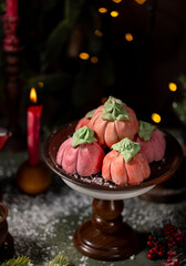Homemade pink marshmallows in the shape of pumpkins surrounded by Christmas decorations.