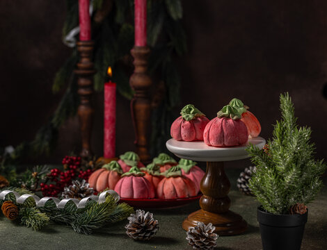 Homemade pink marshmallows in the shape of pumpkins surrounded by Christmas decorations.