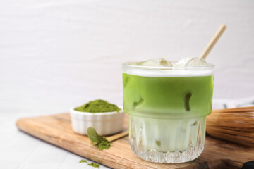 Glass of tasty iced matcha latte on wooden board, closeup. Space for text