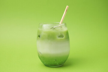 Glass of tasty iced matcha latte on light green background