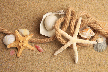 Fototapeta na wymiar Beautiful sea stars, shells and rope on sand, above view