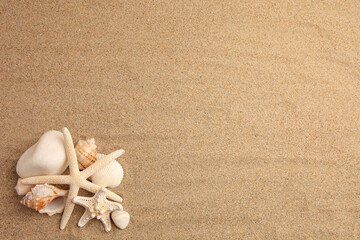 Fototapeta na wymiar Beautiful sea stars, shells and stones on sand, flat lay. Space for text