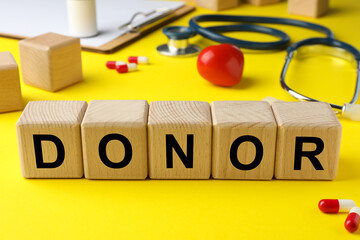 Wooden cubes with word Donor on yellow background