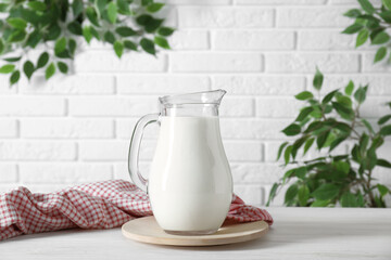 Jug of fresh milk on white wooden table