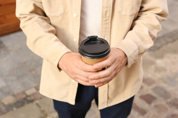 Coffee to go. Man with paper cup of drink outdoors, closeup