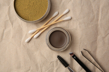Flat lay composition with eyebrow henna and tools on crumpled paper