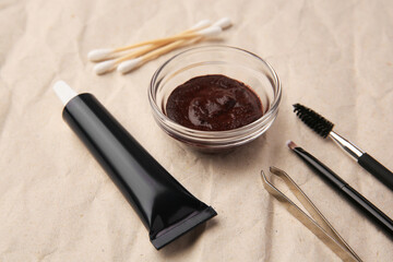 Eyebrow henna and tools on crumpled paper, closeup