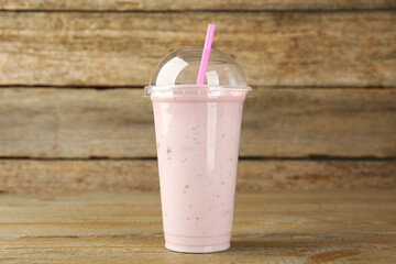 Plastic cup of tasty smoothie on wooden table