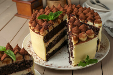 Delicious tiramisu cake with mint leaves on wooden table