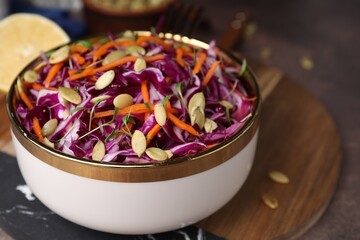 Tasty salad with red cabbage and pumpkin seeds in bowl on table, closeup