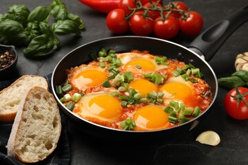 Delicious Shakshuka in frying pan served on grey textured table, closeup