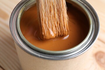Dipping brush into can with wood stain on table, closeup