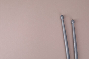 Two gray drum sticks on dusty rose background, top view. Space for text