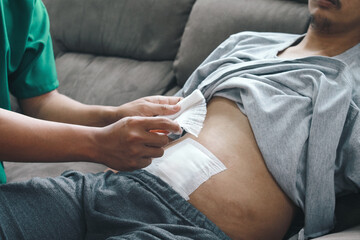 Doctor applying bandage to patient  stomach in the clinic, post appendectomy surgery. 