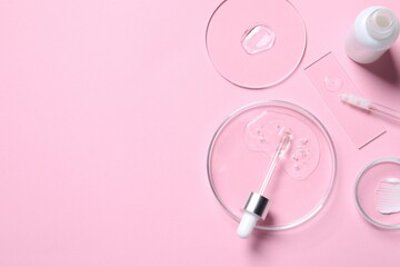Bottle of cosmetic serum and petri dishes with samples on pink background, flat lay. Space for text
